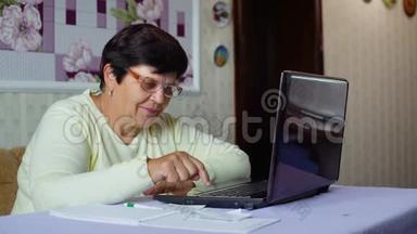 戴眼镜的老年妇女检查家里笔记本电脑的日常<strong>开支</strong>